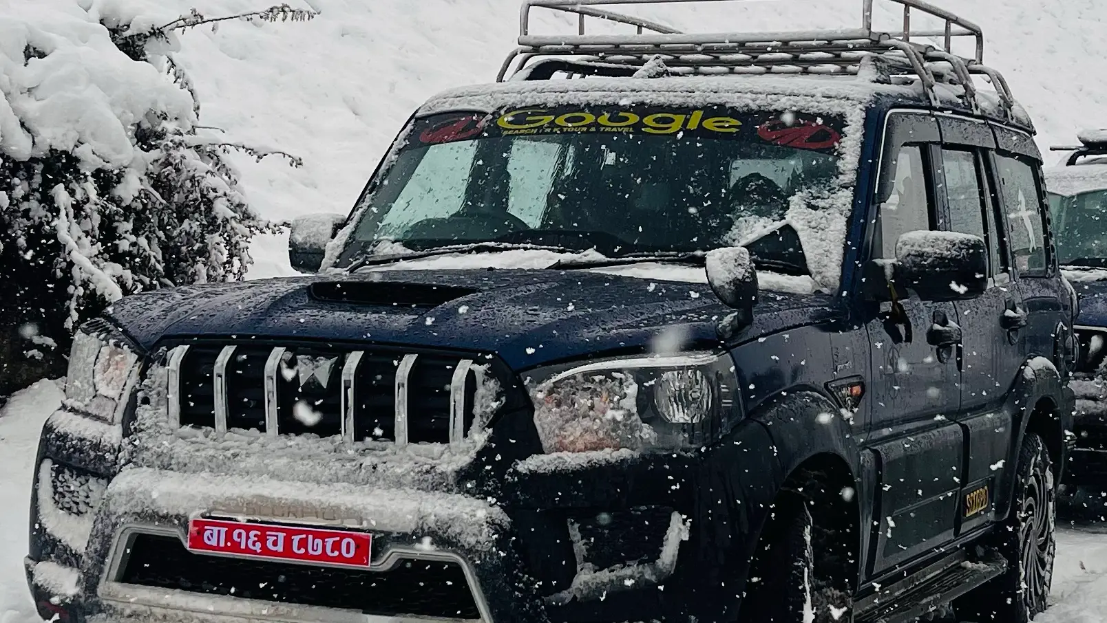 An R.K. Tours Mahindra Scorpio under fresh snow on the Rara route — branded windshield decal visible.
